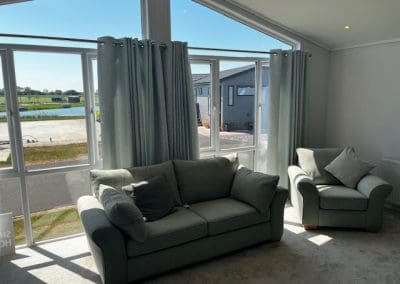 Spacious living area with comfortable seating and scenic lake views at Gateforth Park residential park home